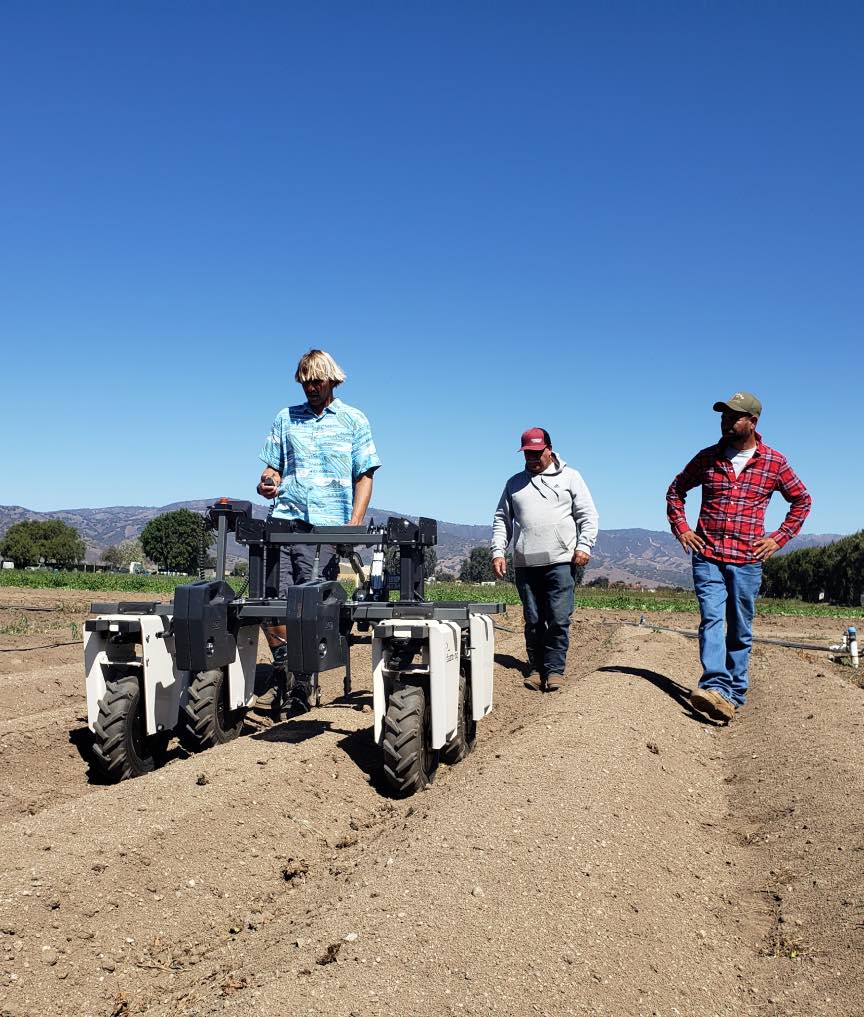 startup employee demonstrating robotic tractor in field 